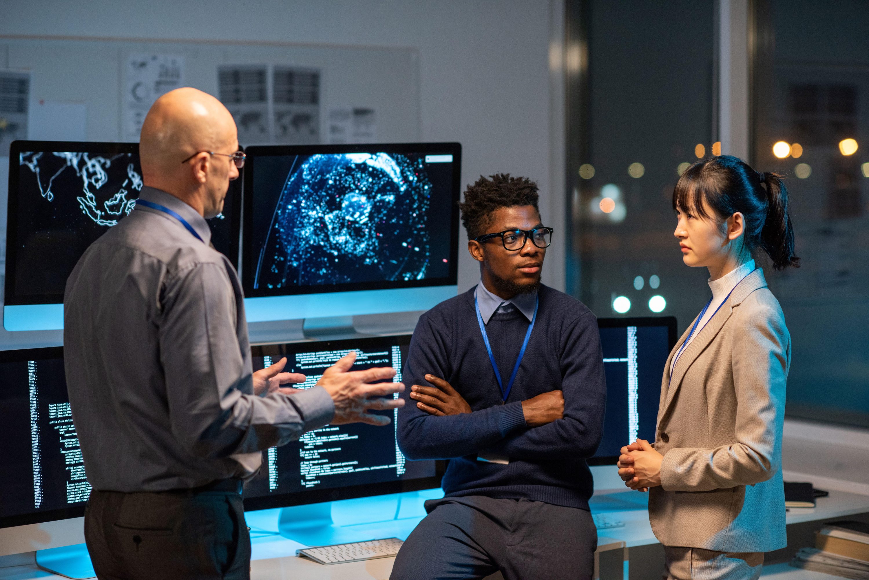 Three focused business professionals gathered next to computer screens